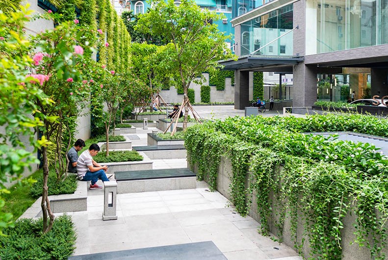 Khu vườn cảnh quan xanh mát và ghế đá thư giãn phía trước Sonatus Building